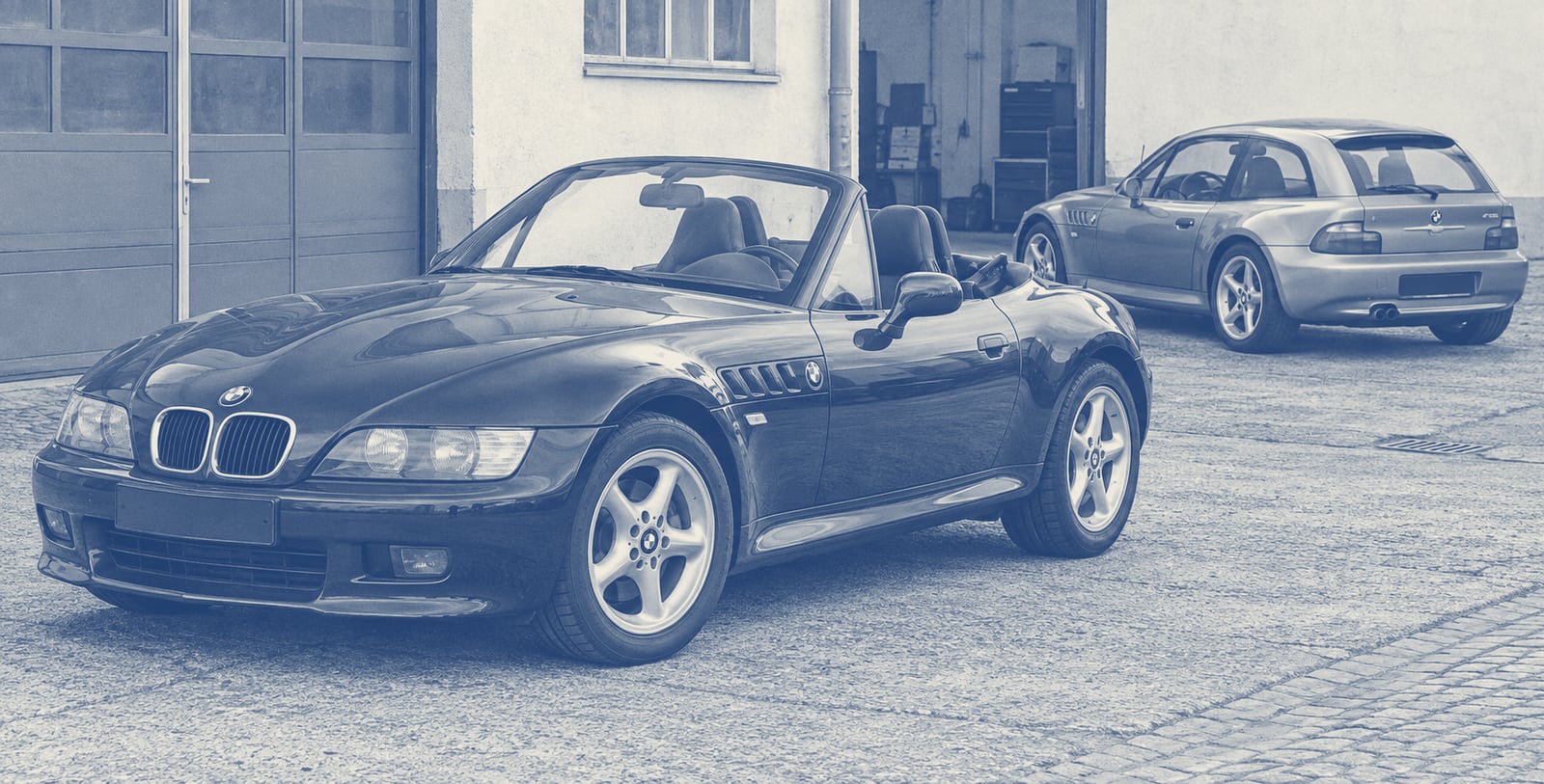 BMW Z3 Roadster schräg von vorn, dahinter ein Z3 Coupé in einem ruhigen Hof.